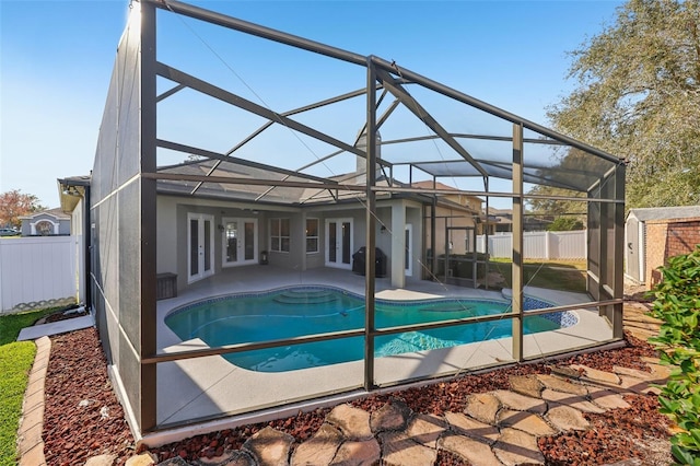 view of pool featuring french doors, a patio, a lanai, and a storage unit