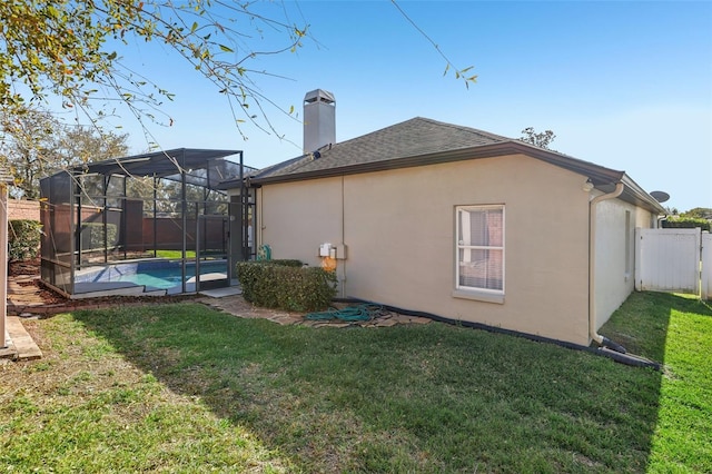 rear view of house featuring a yard, a fenced in pool, and glass enclosure