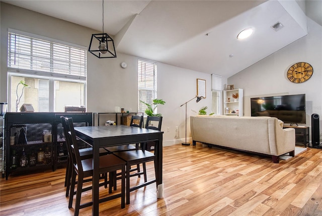 dining space with light wood-type flooring and vaulted ceiling