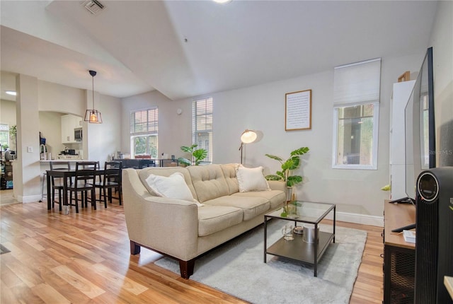 living area with light wood finished floors, visible vents, and baseboards