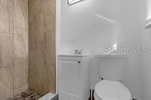 bathroom featuring vanity, toilet, and tiled shower