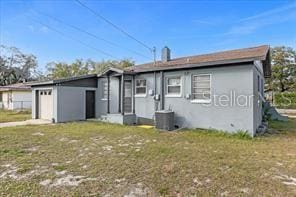 back of property with central AC unit and a lawn