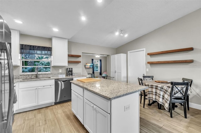 kitchen featuring appliances with stainless steel finishes, sink, white cabinets, a center island, and light stone countertops