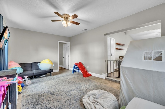 playroom featuring ceiling fan, hardwood / wood-style floors, and a textured ceiling