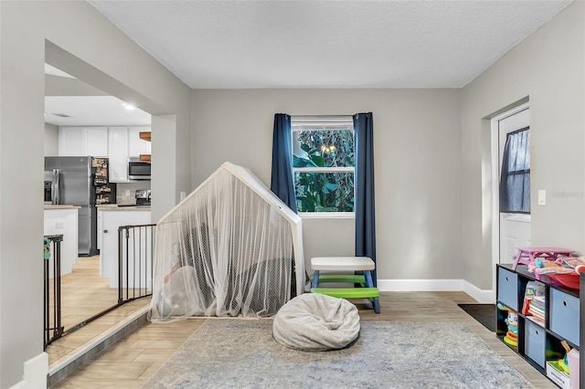 playroom with light hardwood / wood-style flooring and a textured ceiling