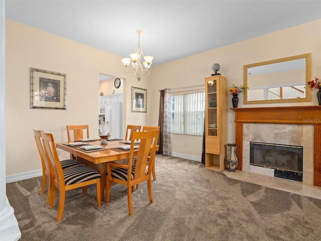 dining area with an inviting chandelier, a tiled fireplace, and carpet floors