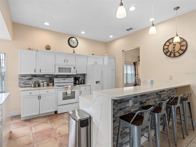 kitchen featuring pendant lighting, white cabinetry, a kitchen bar, kitchen peninsula, and white appliances