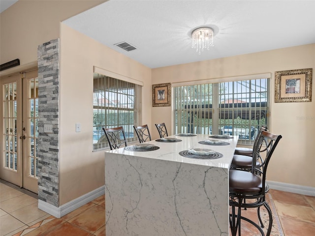 tiled dining space featuring french doors and an inviting chandelier