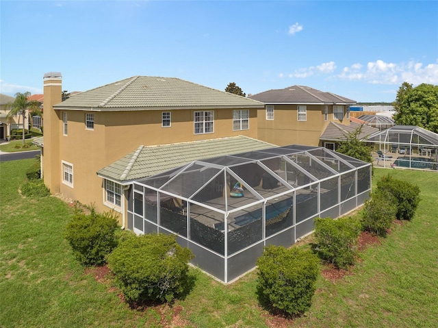 rear view of property featuring a lanai and a lawn