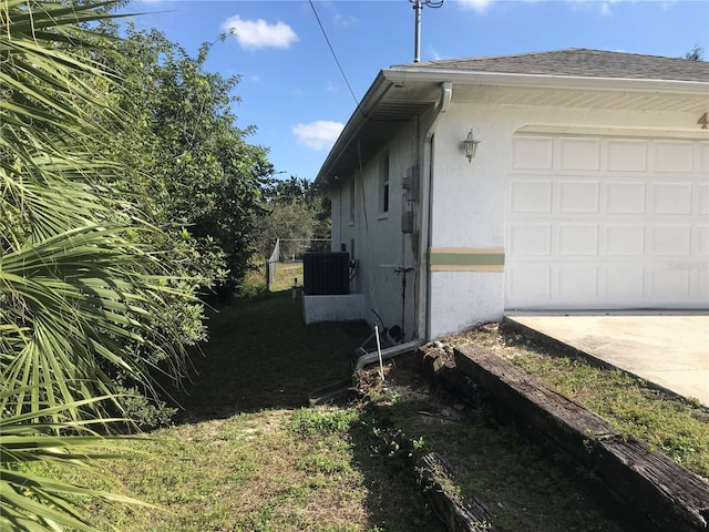 view of side of home with a garage and central air condition unit