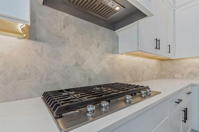 kitchen with stainless steel gas stovetop, white cabinetry, decorative backsplash, and wall chimney exhaust hood