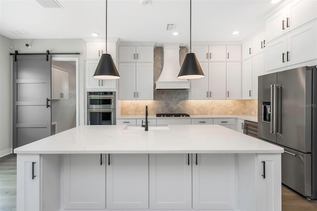 kitchen featuring an island with sink, appliances with stainless steel finishes, sink, and pendant lighting