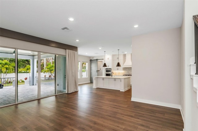 unfurnished living room featuring sink, dark hardwood / wood-style floors, and a barn door