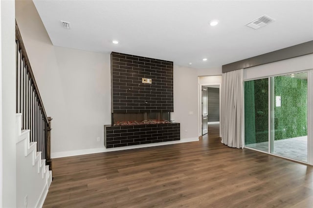 unfurnished living room with a brick fireplace and dark wood-type flooring