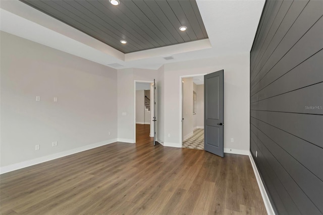 spare room featuring dark hardwood / wood-style flooring, wood ceiling, wooden walls, and a raised ceiling