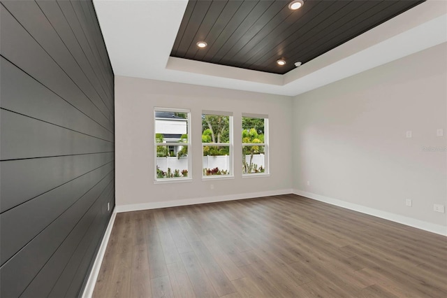 empty room with hardwood / wood-style flooring, a tray ceiling, and wooden ceiling