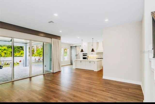 unfurnished living room with a barn door, sink, and light wood-type flooring