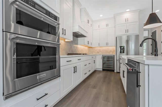 kitchen featuring white cabinets, hanging light fixtures, wine cooler, and stainless steel appliances