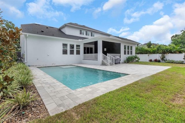 rear view of house featuring a yard, a fenced in pool, and a patio area