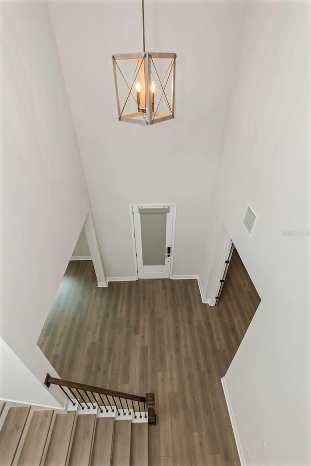 staircase with hardwood / wood-style floors, a chandelier, and a high ceiling