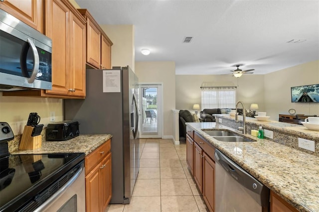 kitchen featuring sink, light stone counters, light tile patterned floors, appliances with stainless steel finishes, and ceiling fan