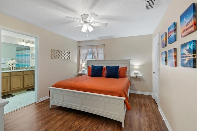 bedroom featuring hardwood / wood-style flooring, ensuite bath, ceiling fan, and a textured ceiling