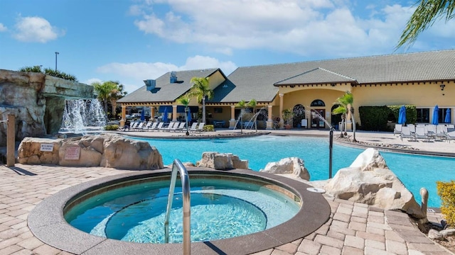 view of pool with pool water feature and a hot tub