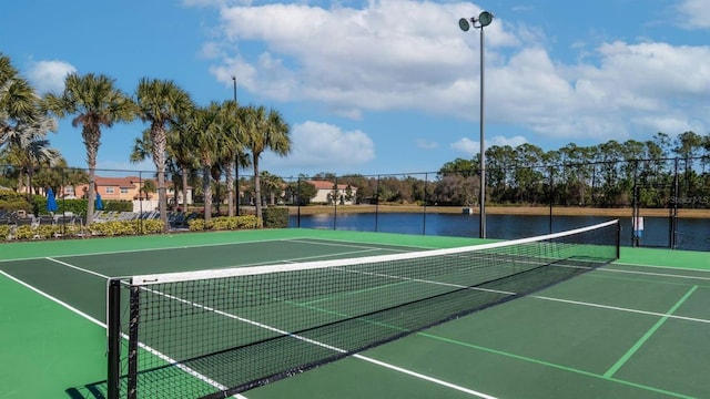 view of tennis court with basketball hoop and a water view