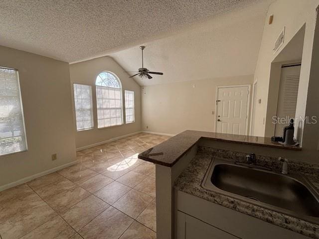 kitchen with vaulted ceiling, sink, light tile patterned floors, ceiling fan, and kitchen peninsula