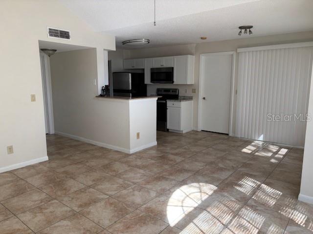 kitchen with lofted ceiling, white cabinets, and black appliances