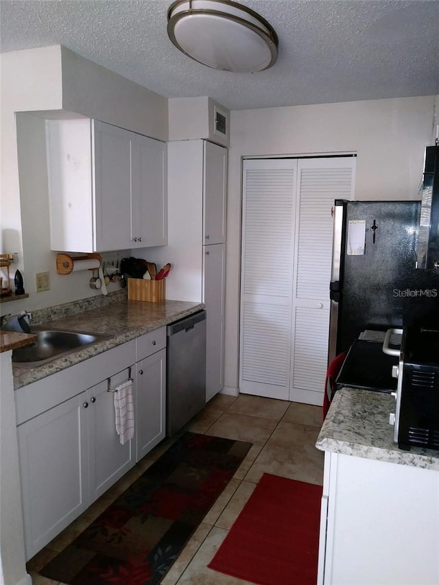 kitchen with sink, light tile patterned floors, stainless steel appliances, and white cabinets