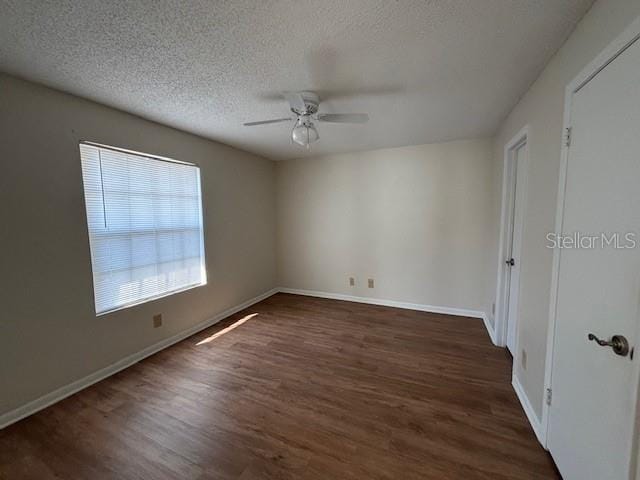 empty room featuring dark wood-type flooring, ceiling fan, and a textured ceiling