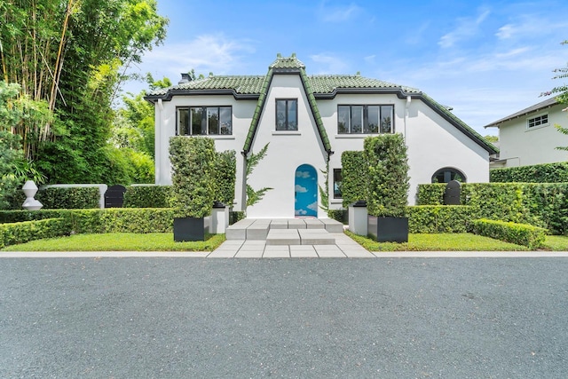 tudor house featuring a tile roof and stucco siding