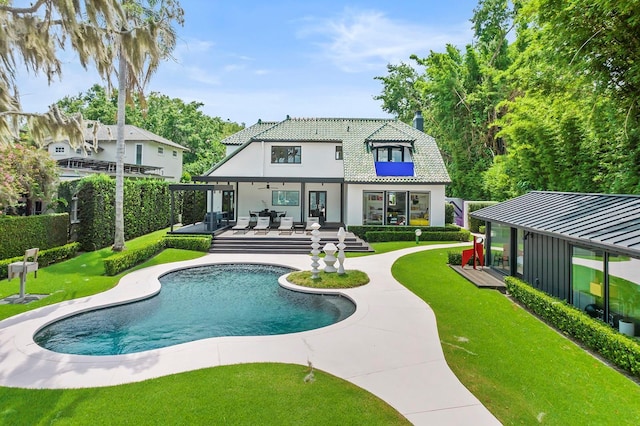 back of property featuring a tiled roof, a lawn, a patio area, and a fenced in pool