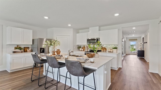 kitchen featuring sink, white cabinetry, appliances with stainless steel finishes, dark hardwood / wood-style flooring, and an island with sink