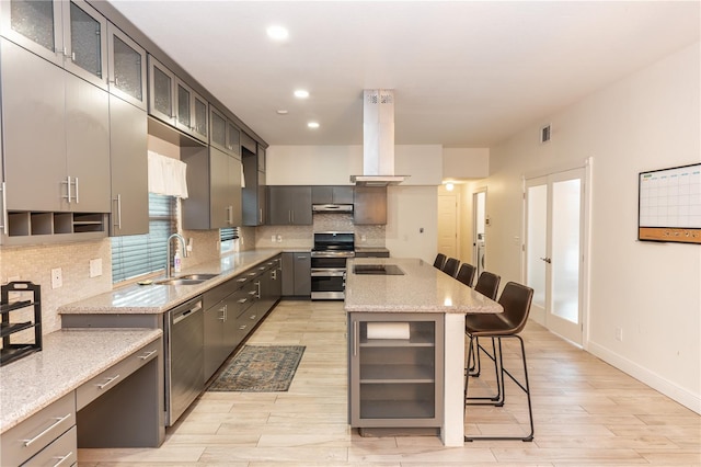 kitchen featuring sink, tasteful backsplash, appliances with stainless steel finishes, a kitchen breakfast bar, and a kitchen island