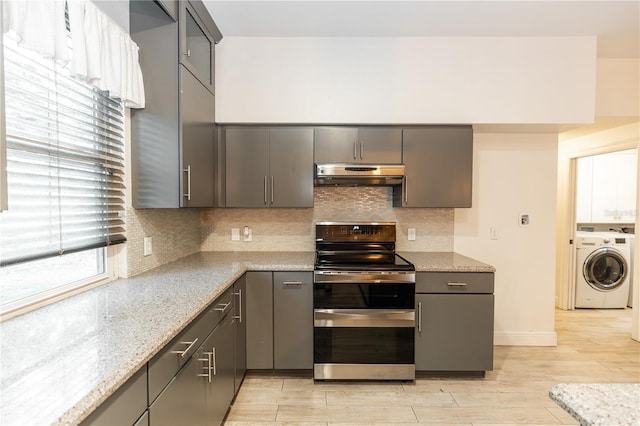 kitchen featuring gray cabinets, tasteful backsplash, light stone countertops, washer / clothes dryer, and range with two ovens