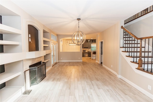 unfurnished living room with an inviting chandelier and light wood-type flooring