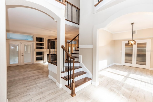 stairs with hardwood / wood-style flooring, built in shelves, a high ceiling, and french doors