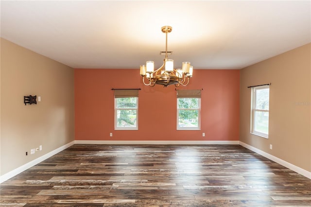 unfurnished room with an inviting chandelier and dark wood-type flooring