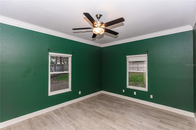 spare room featuring a healthy amount of sunlight, ornamental molding, and light hardwood / wood-style flooring