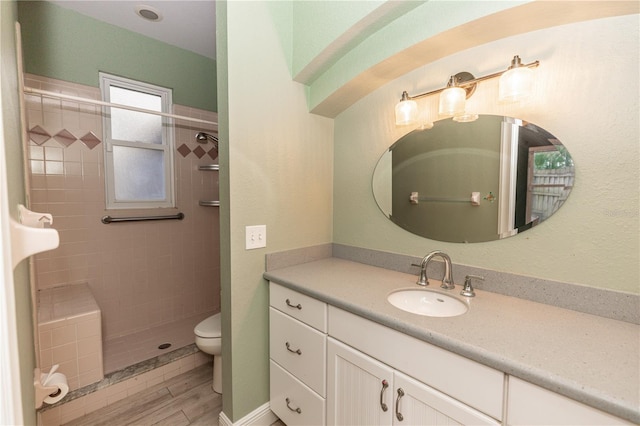 bathroom with vanity, hardwood / wood-style flooring, toilet, and tiled shower