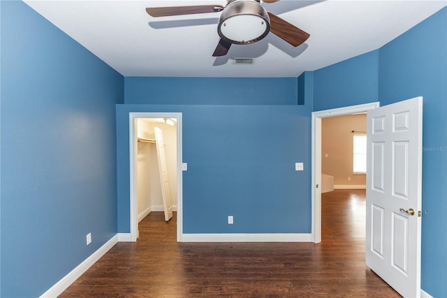 unfurnished bedroom with dark wood-type flooring, ceiling fan, a spacious closet, and a closet