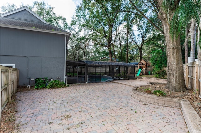 view of patio featuring a playground, a lanai, and a fenced in pool