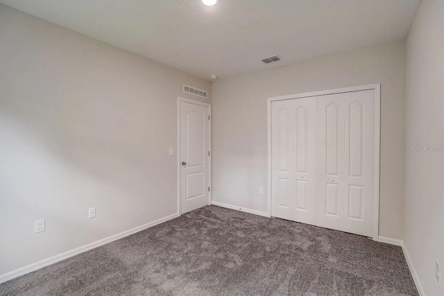 unfurnished bedroom featuring a closet and dark colored carpet