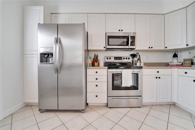 kitchen featuring stainless steel appliances, light tile patterned floors, and white cabinets