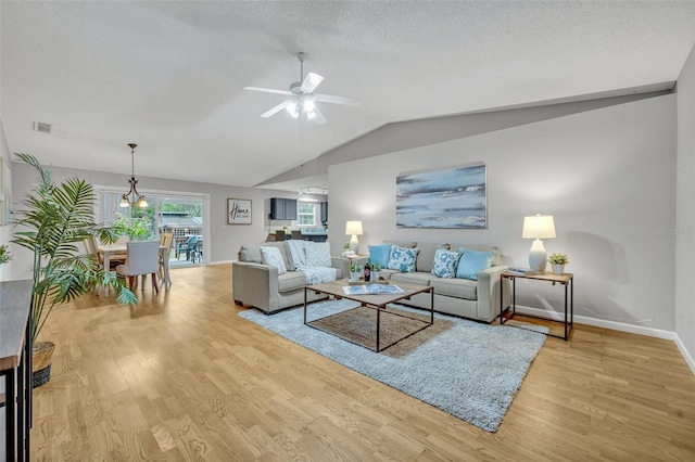 living room with ceiling fan, vaulted ceiling, light hardwood / wood-style floors, and a textured ceiling