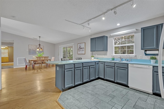 kitchen with lofted ceiling, sink, a textured ceiling, white dishwasher, and pendant lighting