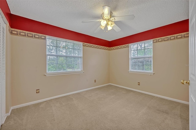 carpeted empty room with ceiling fan and a textured ceiling