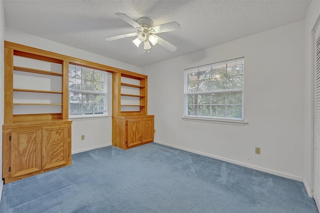 unfurnished room featuring ceiling fan, plenty of natural light, a textured ceiling, and carpet flooring